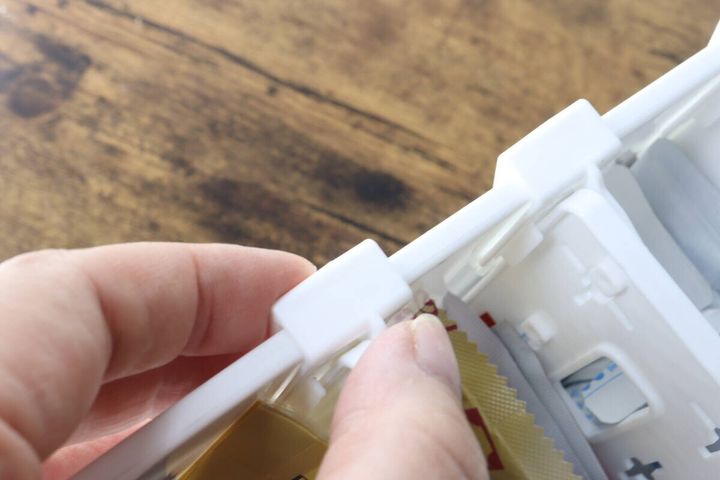 白い収納ボックスのフチに仕切り板のフックを固定する手元