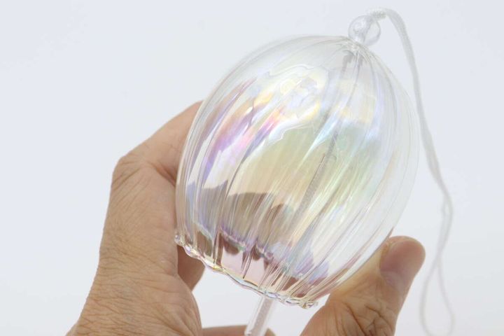 オーロラ加工のガラス風鈴本体を女性の手が持ち、光にかざしている様子
