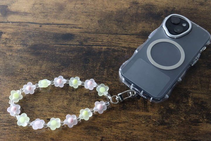 スマホケースに装着されたパステルカラーのお花ビーズストラップ