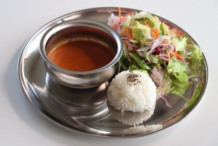 ステンレス皿にカレーポット、ライス、サラダが盛り付けられた様子