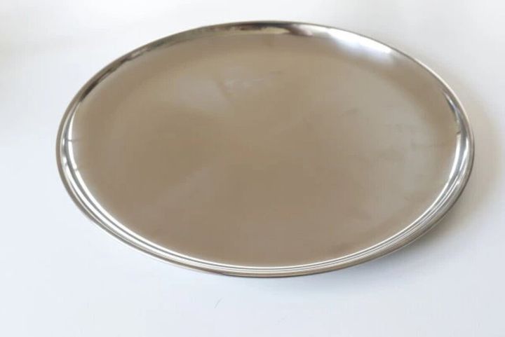 白い背景に置かれた光沢のあるステンレス製カレー皿