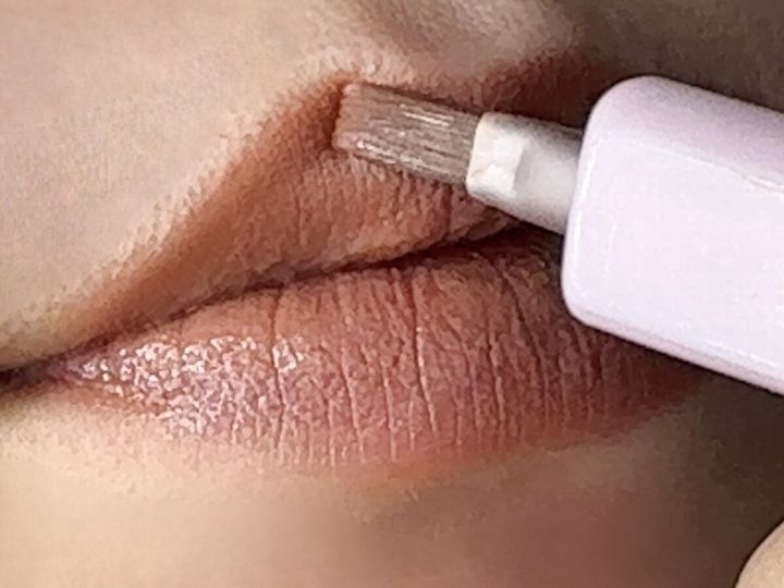 女性が唇にスライド式リップブラシで口紅を塗っている様子