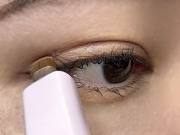 女性が目の下の涙袋にスライド式アイシャドウブラシを使っている様子