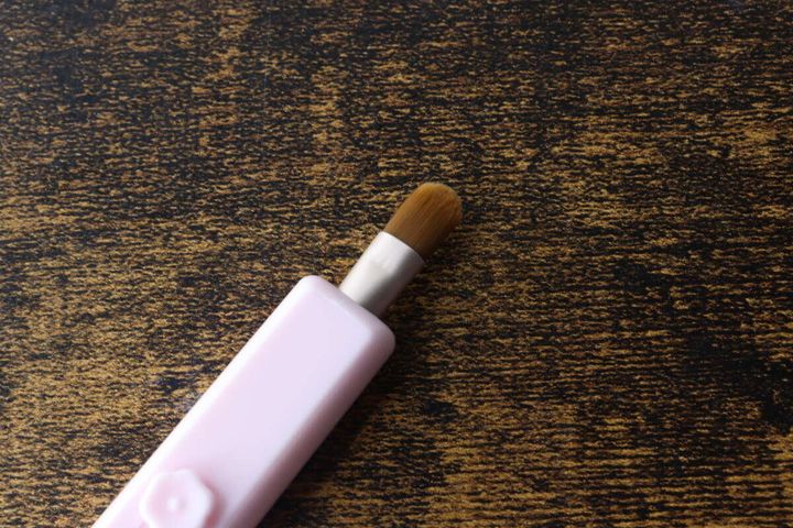 ピンク色のスライド式アイシャドウブラシのブラシ部分が本体から出ている状態