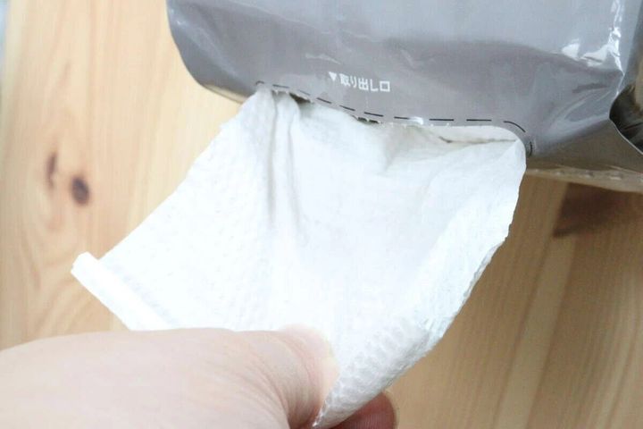 パッケージの取り出し口からペーパータオルを一枚引き出す手