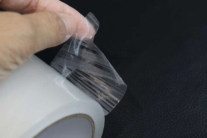 透明な梱包テープの端を指で剥がしているアップ