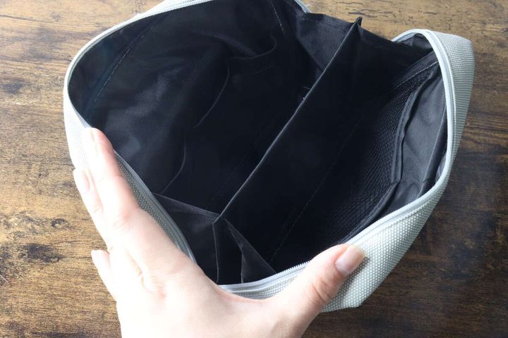 女性の手がガジェットポーチのファスナーを開け、内部の仕切りが見える