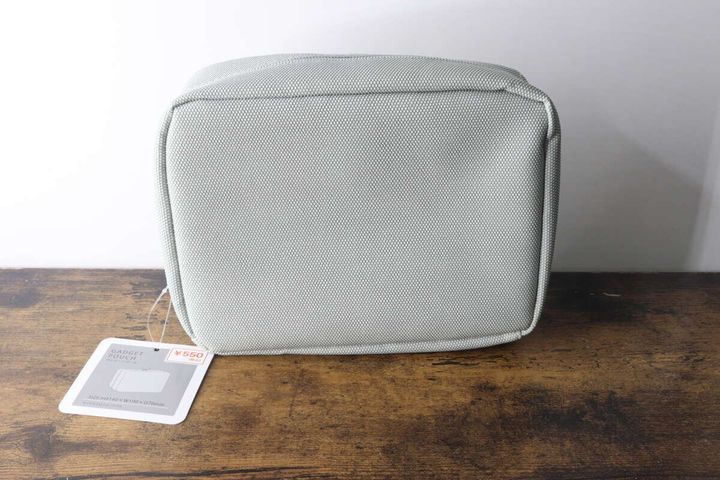 グレーのガジェットポーチが木製のテーブルに置かれ、値札が付いている