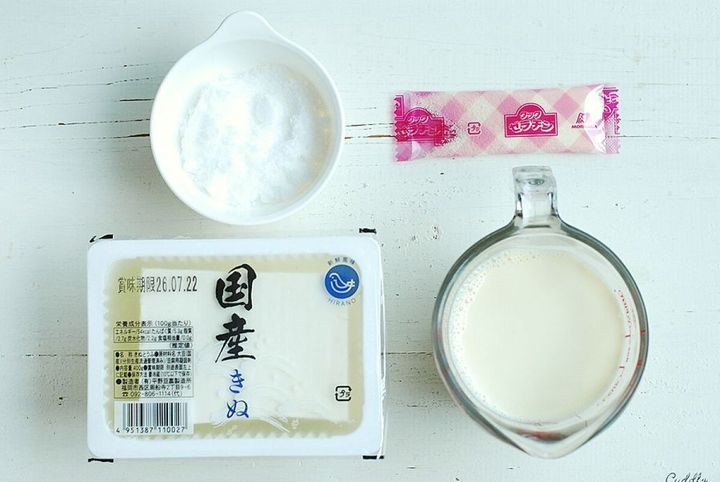 白い木目のテーブルに絹ごし豆腐、豆乳、砂糖、粉ゼラチンが並べられた俯瞰写真