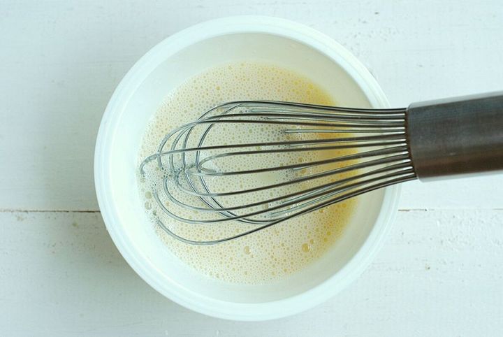 白いボウルに入った豆乳と砂糖、ゼラチンを泡立て器で混ぜている様子を上から撮影