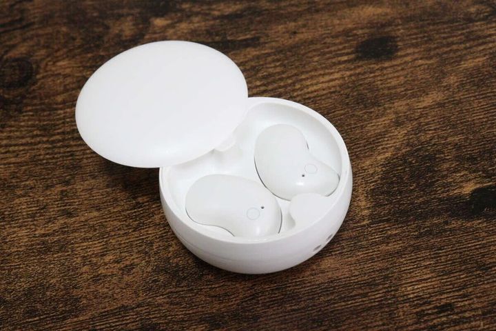 木目調のテーブルに置かれた、白い丸い充電ケースと寝ホン