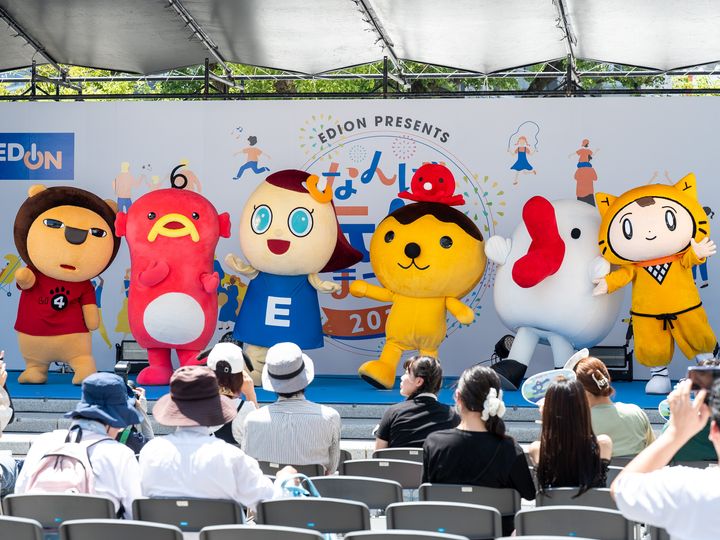 ステージに横一列で並ぶ在阪テレビ局のマスコットキャラクターとエディオンのいいなちゃん