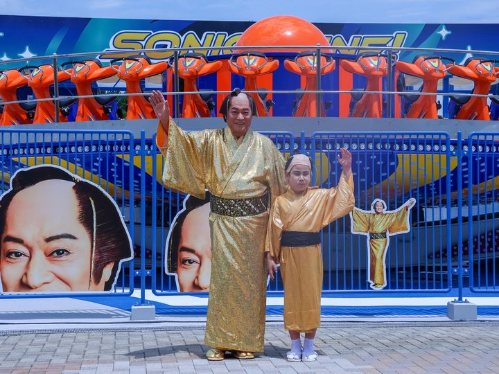 『SONIC TUNE!』の前で手を上げる松平健さんと金の着物を着た子ども