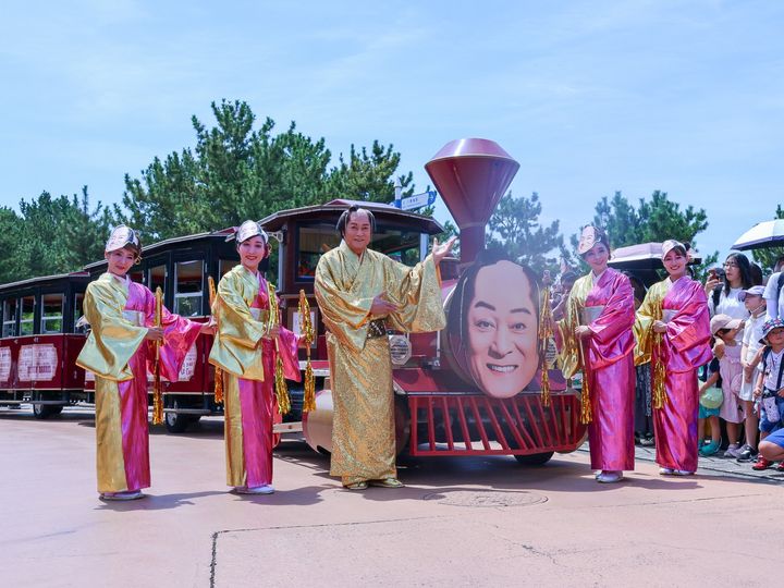 マツケンの顔を模した汽車の前に立つ松平健さんと着物姿のダンサーたち