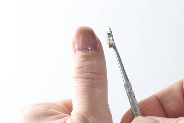 親指の爪の横にマグネットツールを近づける様子