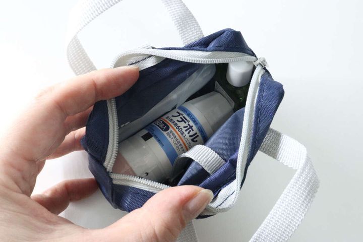 手がポーチのメイン収納に常備薬や目薬などの小物を入れている