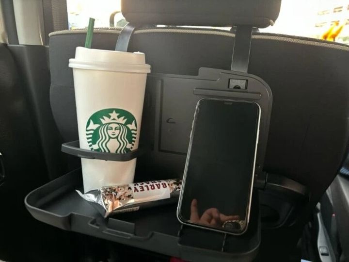 後部座席のリアシートトレイに飲み物とお菓子、スマホが置かれている