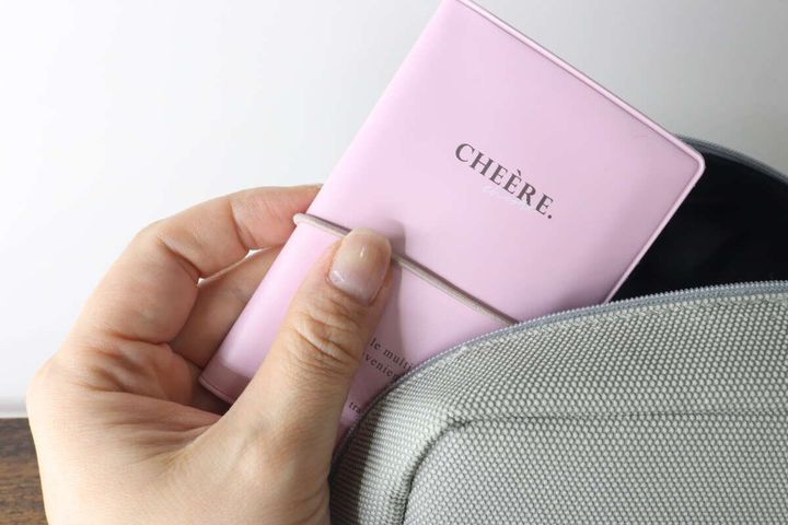 ピンク色のマルチホルダーをグレーのバッグに入れている手元