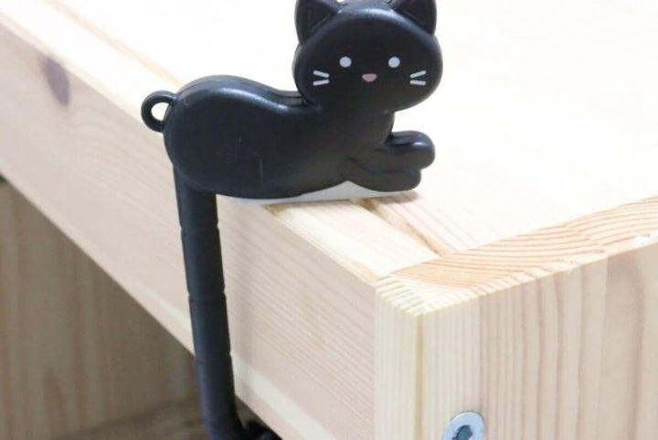 黒い猫型バッグフックが木製テーブルに引っ掛けられている