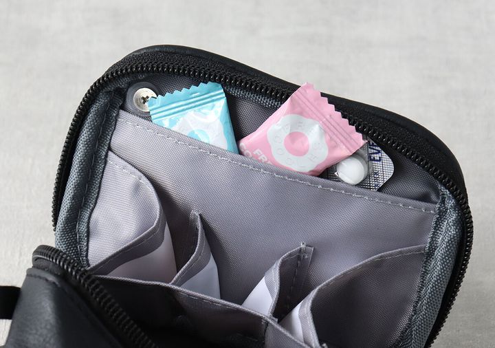 黒いコンパクトポーチのミニポケットに薬と飴が入っている