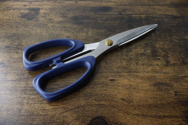 木目調のテーブルに置かれたネイビーの厚刃キッチンハサミ
