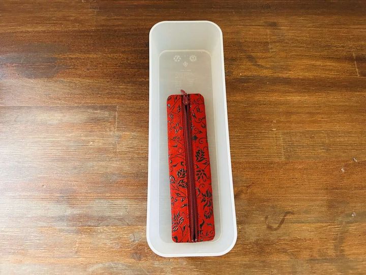 白い長方形のボックスに赤い花柄の筆箱が一つだけ入っている