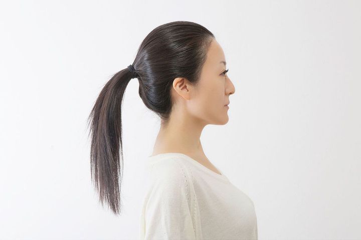 長い髪の毛を後ろで一つに束ねた女性