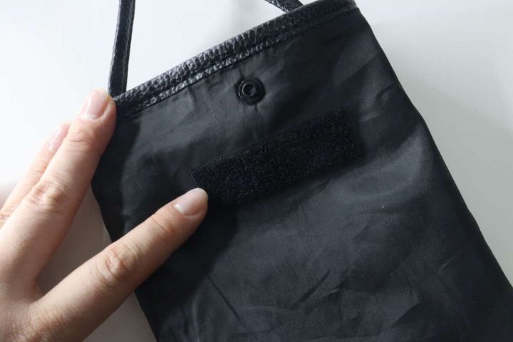 女性が黒いサコッシュの内側に面ファスナーを貼っている