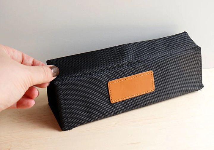 黒い布製ポーチを指で触る女性の手元