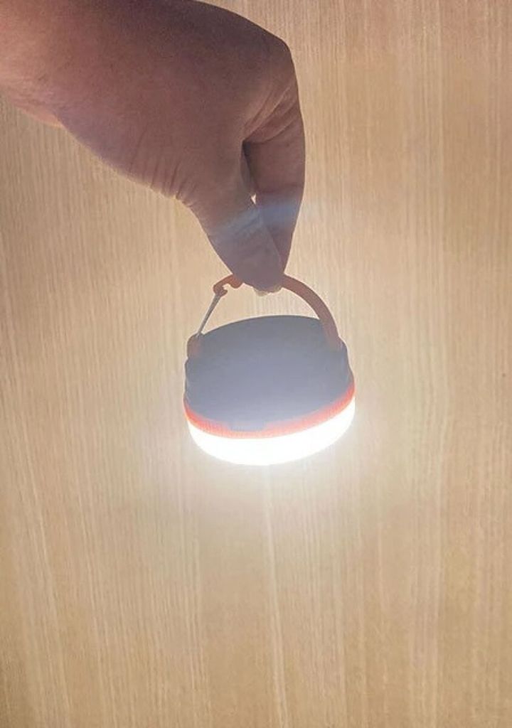 手で吊るされ明るく点灯する小型ランタン