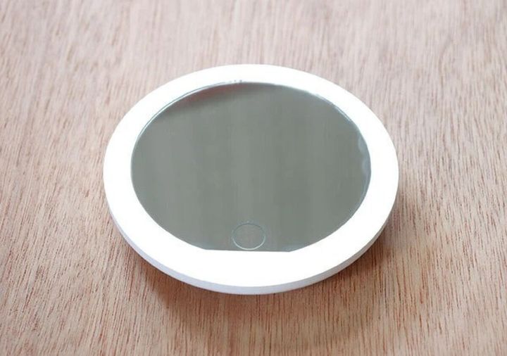 木目テーブルに置かれた白い丸型LEDミラー