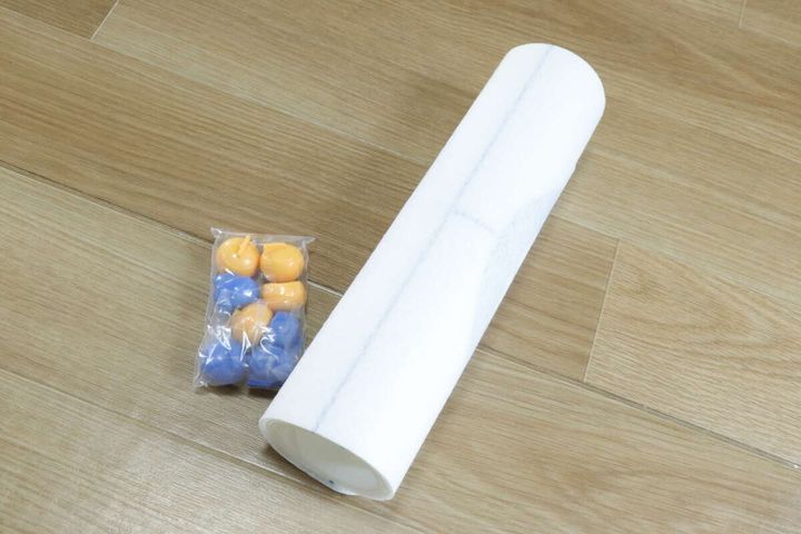 巻かれた白いカーリングマットとストーンの袋