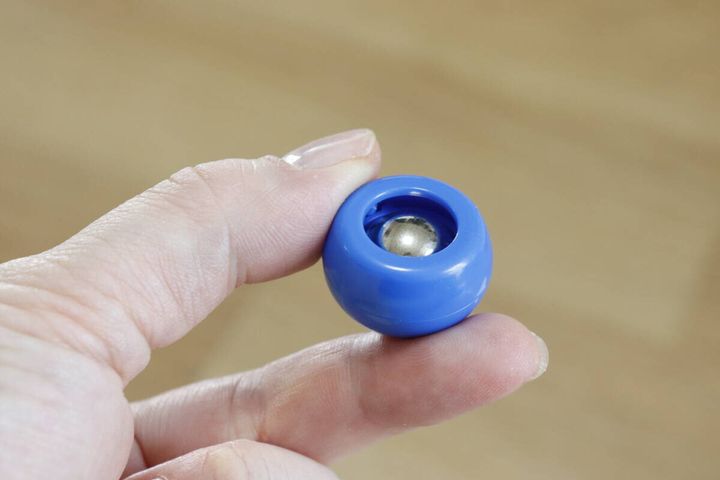 指で持った青いカーリングストーンの裏側にある鉄玉