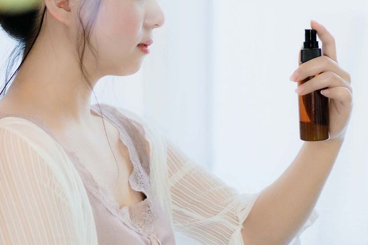 顔にミスト・スプレーをかける女性