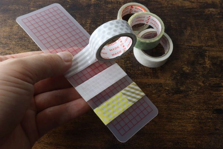 手で巻き板を持ち、マスキングテープを巻きつけている様子