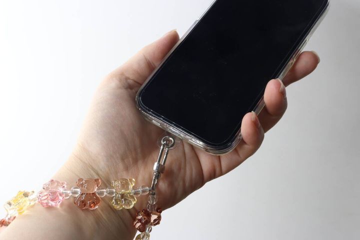 女性がスマホを手に持ちストラップを手首に通している様子