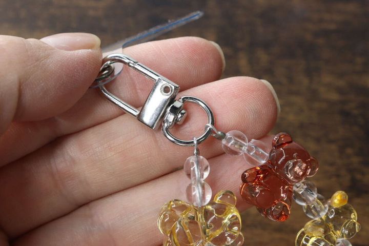 指でつまんだスマホストラップの回転式カラビナ金具