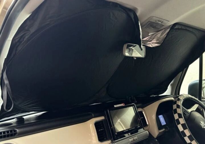 車のフロントガラスに設置され日差しを防いでいる黒いサンシェード