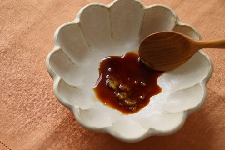 小皿に醤油とわさびを入れ、木のスプーンで混ぜている様子