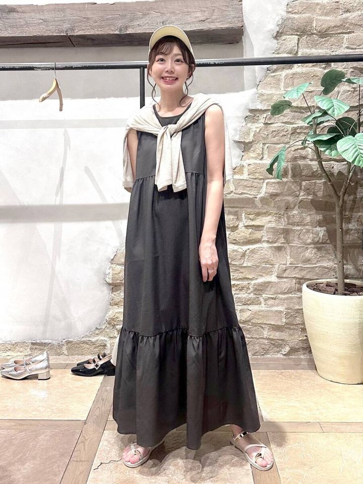 黒ノースリーブワンピにベージュカーデを羽織った女性