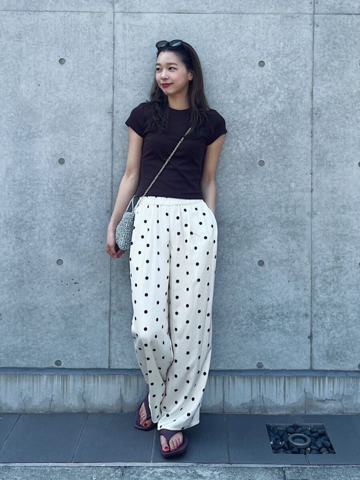 黒Tシャツとドット柄ワイドパンツの女性