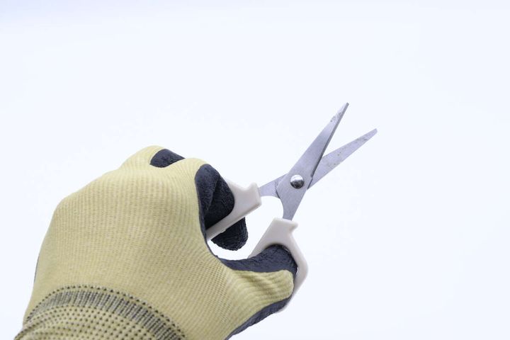 吸水速乾背抜き手袋を着用した手が小さなハサミを握っている