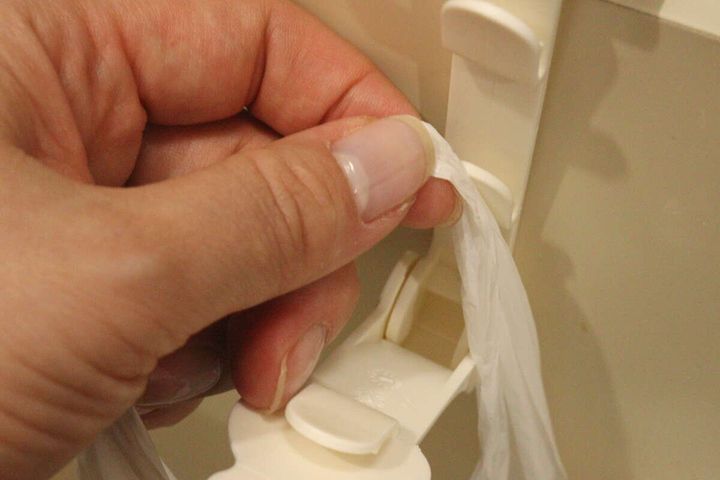 女性の手が広口袋ホルダーにゴミ袋をセット