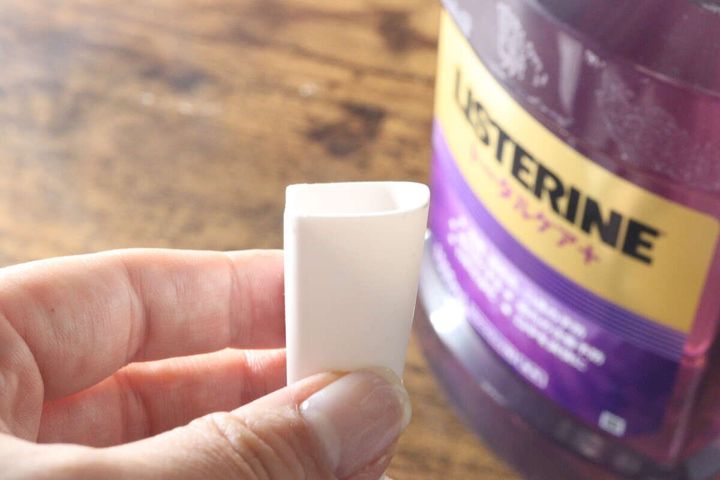 マウスウォッシュコップの片側が長い注ぎ口を指で示している様子