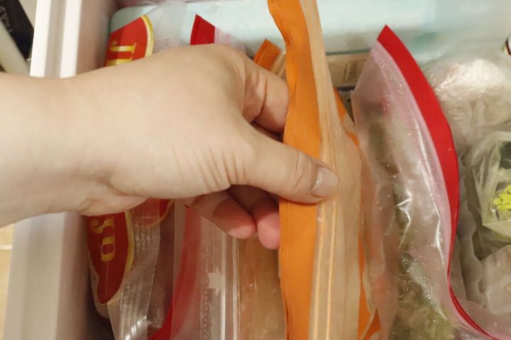 冷凍庫から立てて収納された冷凍食品を、手がスムーズに取り出している様子