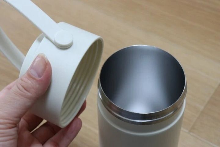 白いペットボトルホルダーの蓋を片手で開けている