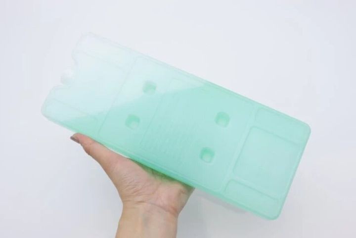 半透明の緑色のハードタイプ保冷剤を片手で持っている
