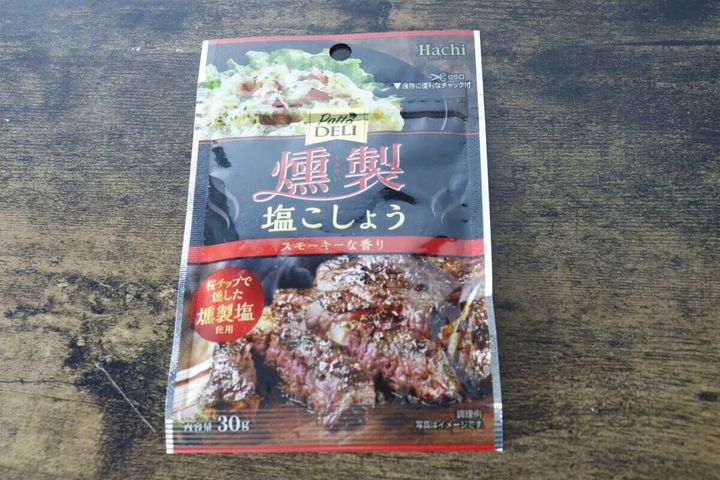 「PattoDELI 燻製塩こしょう」の黒いパッケージが木目のテーブルに置かれている