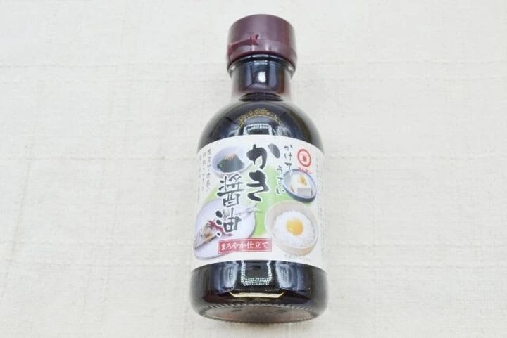 「マルキン かけて、うまいかき醤油」のボトルが白い背景に置かれている