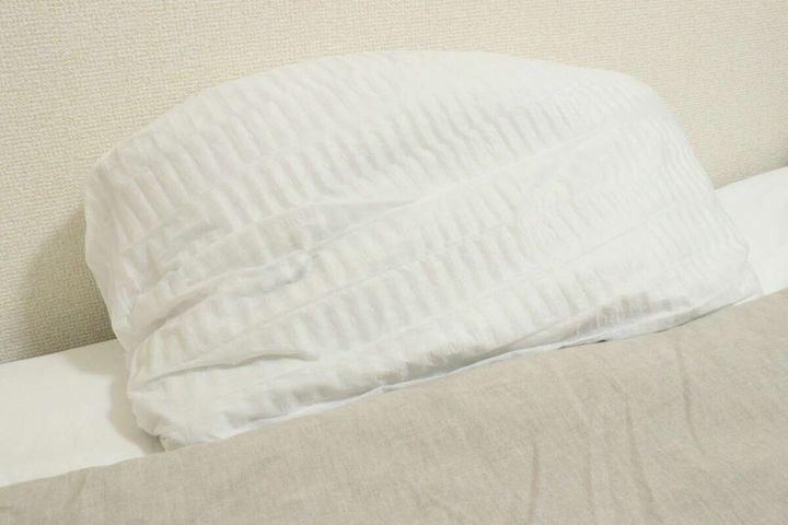 ベッドに置かれた白い不織布まくらカバーが装着されたまくら